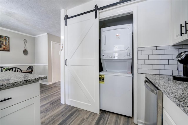 6700 Roswell Rd Unit 32C, Atlanta, GA 30328 - washroom with estacked washer and dryer, a barn door, dark wood-style flooring, and a textured ceiling