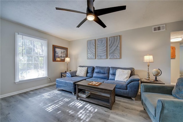 living area with light wood-type flooring, baseboards, visible vents, and ceiling fan