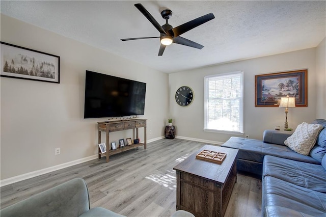 living area featuring ceiling fan, a textured ceiling, light wood-type flooring, and baseboards