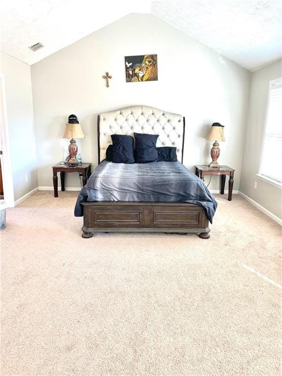 bedroom with light colored carpet, lofted ceiling, and a textured ceiling