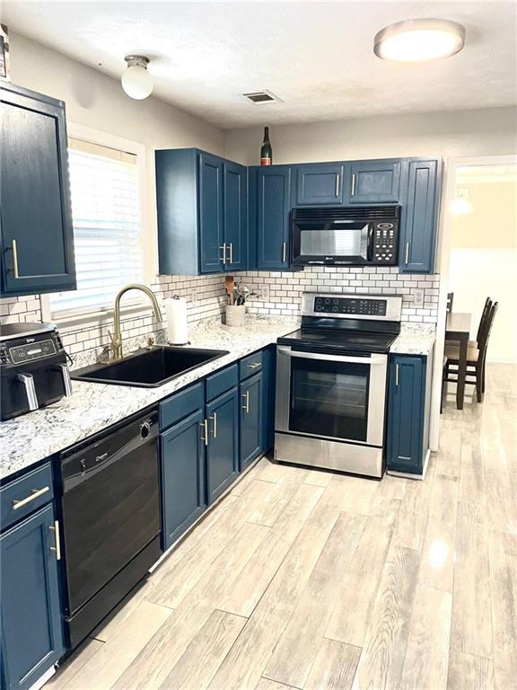 kitchen with sink, black appliances, and blue cabinets