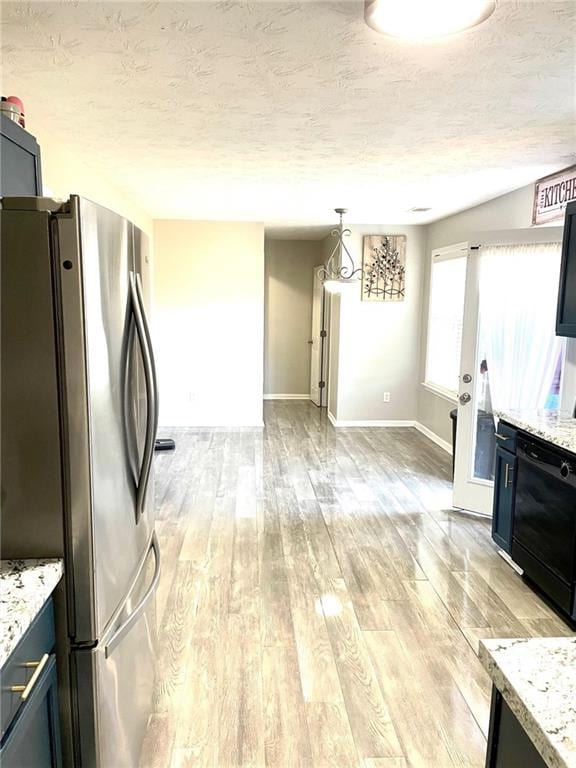 kitchen with hanging light fixtures, light hardwood / wood-style flooring, stainless steel fridge, light stone countertops, and a textured ceiling