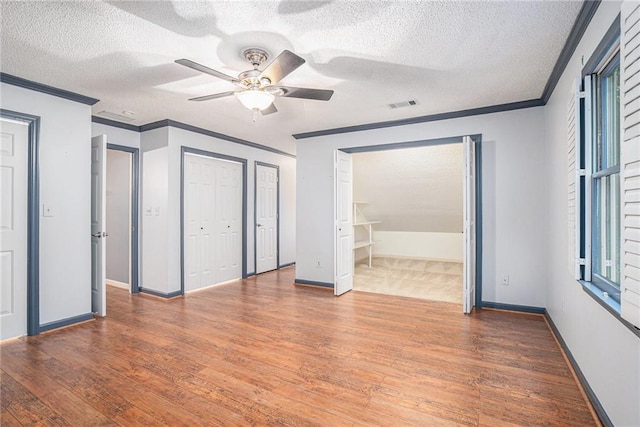 1488 White Columns Blvd, Canton, GA 30115 - unfurnished bedroom featuring wood finished floors, crown molding, multiple closets, a textured ceiling, and a ceiling fan