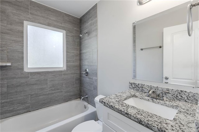 full bathroom featuring tiled shower / bath, vanity, and toilet