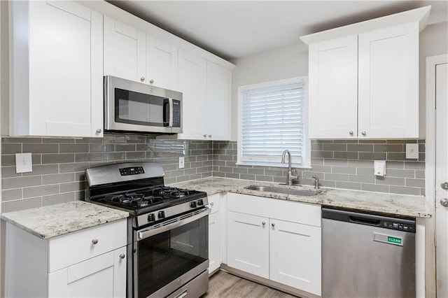 kitchen with white cabinetry, sink, stainless steel appliances, and light stone counters