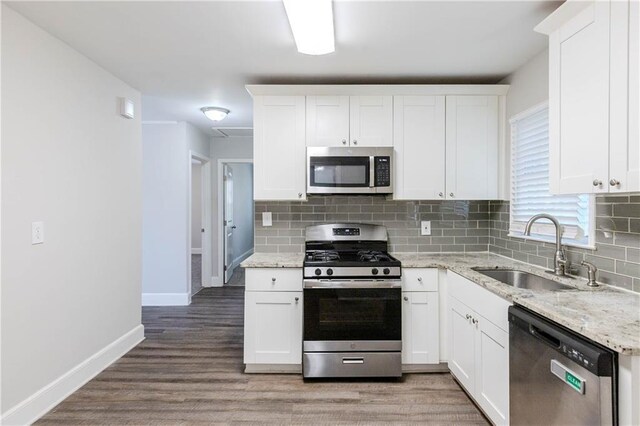 kitchen with light stone countertops, sink, white cabinetry, and stainless steel appliances