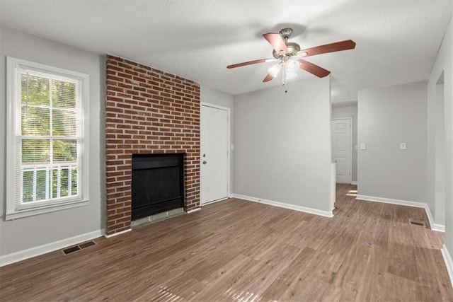 unfurnished living room with wood-type flooring, a fireplace, and ceiling fan