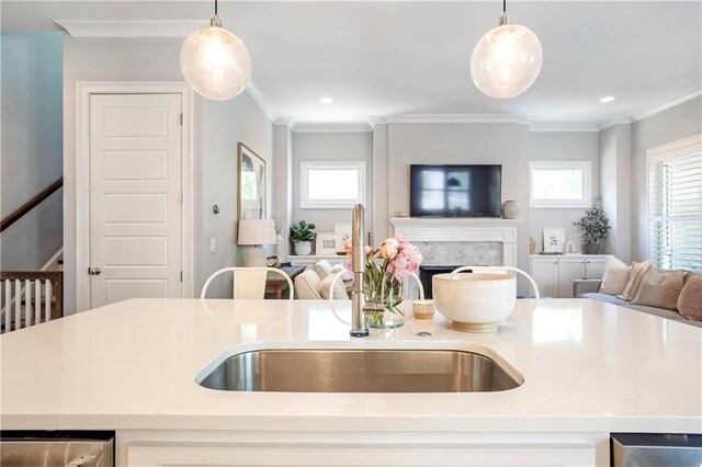 kitchen with a sink, hanging light fixtures, crown molding, and open floor plan