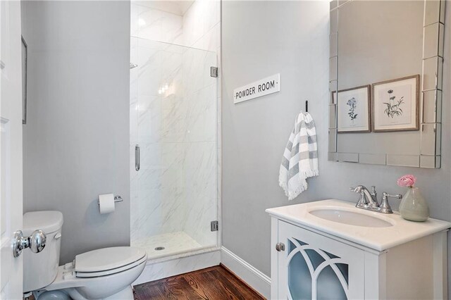 bathroom featuring toilet, a shower stall, wood finished floors, and vanity
