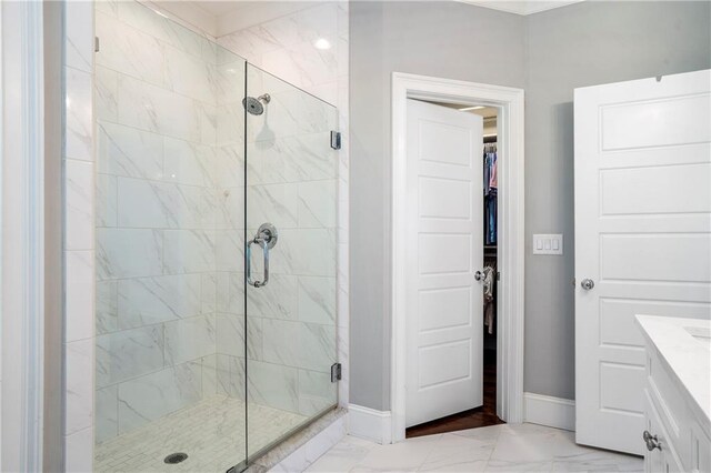 full bath with baseboards, marble finish floor, a walk in closet, and a shower stall