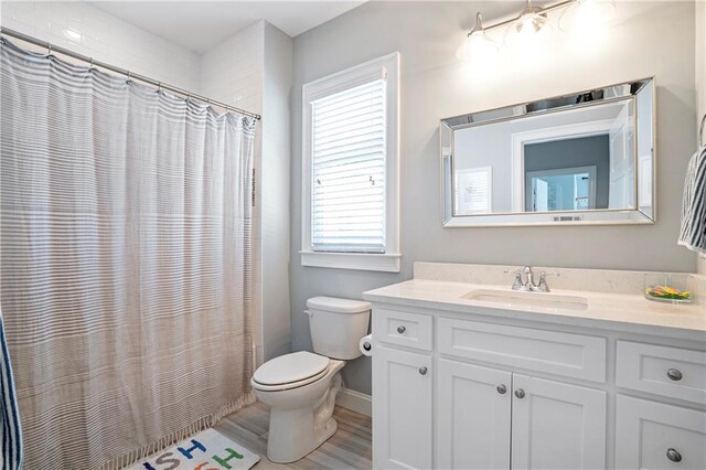 bathroom featuring vanity, baseboards, a wealth of natural light, and toilet