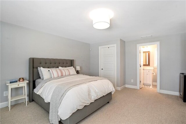 bedroom featuring baseboards, connected bathroom, visible vents, and light carpet