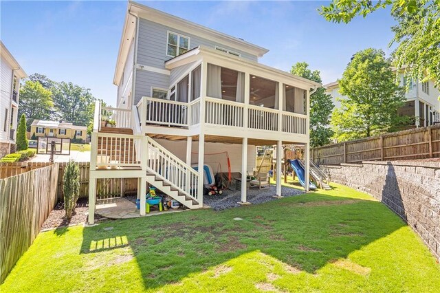 rear view of property featuring a fenced backyard, a sunroom, and a yard
