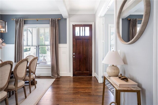 entrance foyer featuring crown molding, wood finished floors, and a wainscoted wall