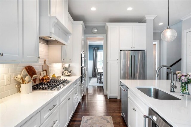kitchen with appliances with stainless steel finishes, a sink, custom exhaust hood, white cabinetry, and dark wood-type flooring