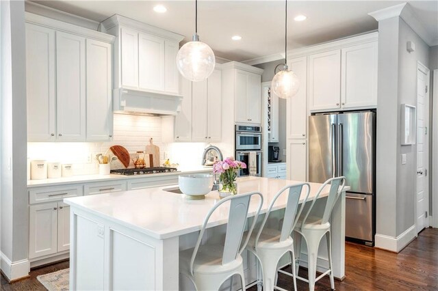 kitchen with white cabinetry, appliances with stainless steel finishes, a center island with sink, and dark wood finished floors