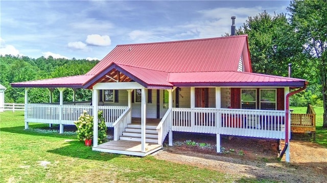 view of front of home with covered porch, metal roof, and a front yard