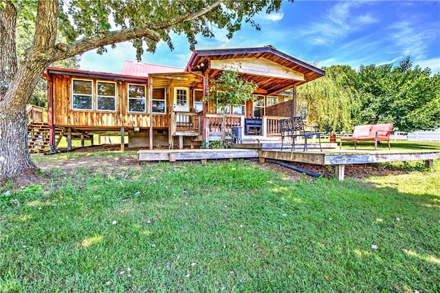 rear view of house featuring a wooden deck and a lawn