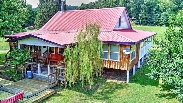 back of property featuring a yard and metal roof