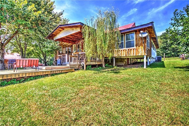 back of property featuring metal roof, central AC, a lawn, and a wooden deck