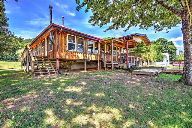 rear view of house featuring a lawn and a deck