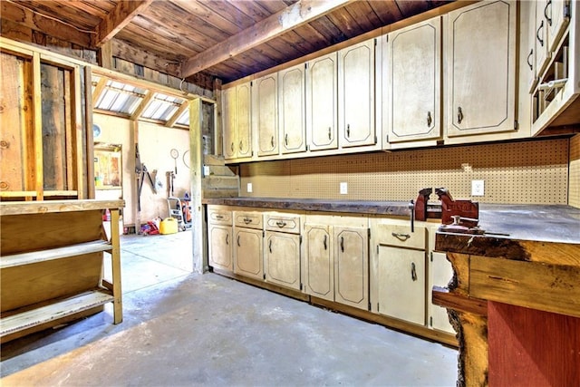 kitchen featuring dark countertops, wood ceiling, unfinished concrete flooring, and beamed ceiling