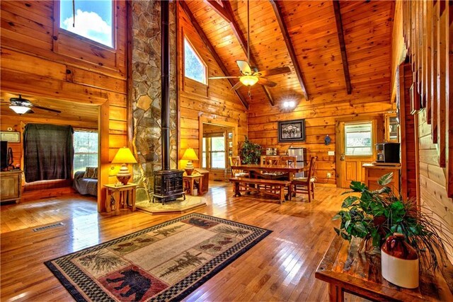 living room featuring ceiling fan, wood-type flooring, plenty of natural light, and a wood stove