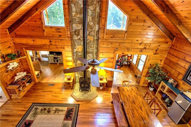 living room with ceiling fan, light wood-type flooring, wood ceiling, wood walls, and plenty of natural light