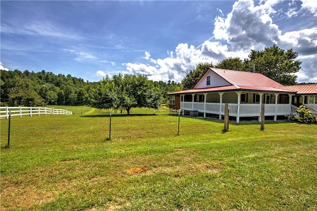 view of yard with covered porch and fence