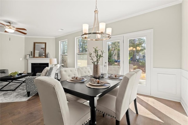 dining room with crown molding, a fireplace, dark wood finished floors, and a healthy amount of sunlight