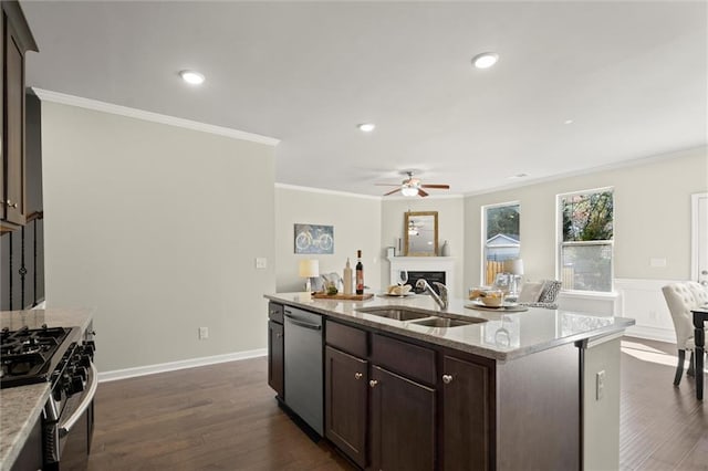 kitchen with a fireplace, stainless steel appliances, open floor plan, a sink, and an island with sink