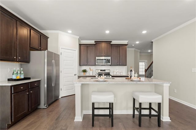 kitchen with an island with sink, a breakfast bar area, stainless steel appliances, and dark wood-style flooring