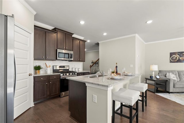 kitchen with a breakfast bar, dark wood-style flooring, a sink, open floor plan, and appliances with stainless steel finishes