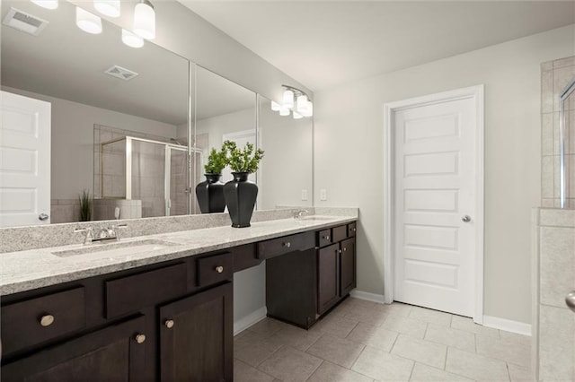 full bath with double vanity, a sink, visible vents, and a shower stall