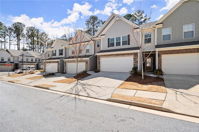 view of property featuring concrete driveway, brick siding, an attached garage, and a residential view