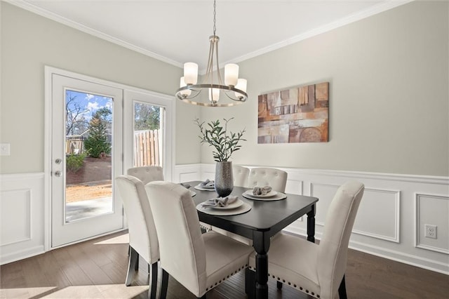 dining room with dark wood-style floors, a chandelier, crown molding, and wainscoting