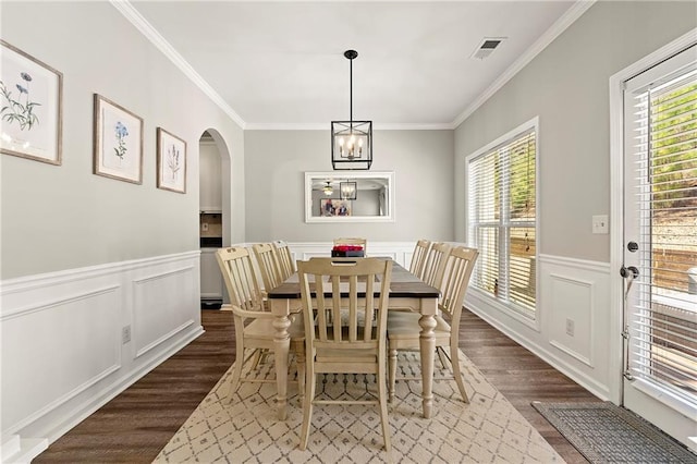 dining room with visible vents, ornamental molding, wood finished floors, arched walkways, and a chandelier