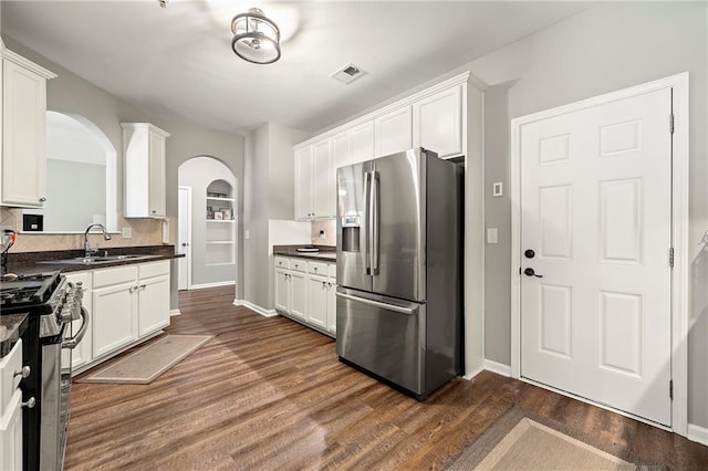 kitchen featuring dark countertops, dark wood-style flooring, appliances with stainless steel finishes, and a sink