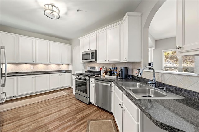 kitchen featuring a sink, stainless steel appliances, dark countertops, and white cabinetry