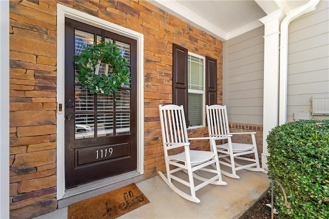 entrance to property with brick siding and a porch