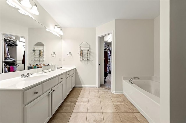 full bathroom with a garden tub, baseboards, double vanity, a sink, and tile patterned floors