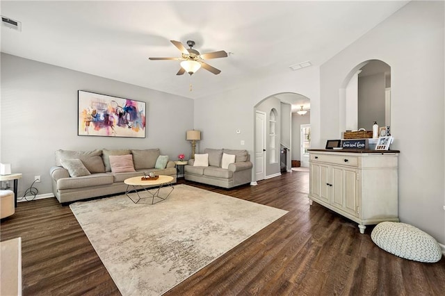 living room with dark wood finished floors, visible vents, and baseboards