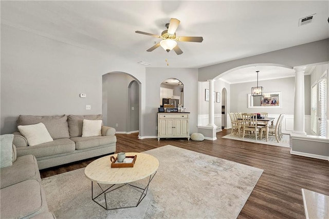 living room featuring a ceiling fan, decorative columns, dark wood-style floors, and visible vents