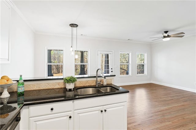 kitchen featuring sink, crown molding, white cabinetry, hardwood / wood-style flooring, and hanging light fixtures