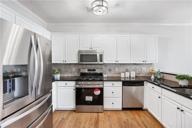 kitchen featuring tasteful backsplash, white cabinets, appliances with stainless steel finishes, and ornamental molding