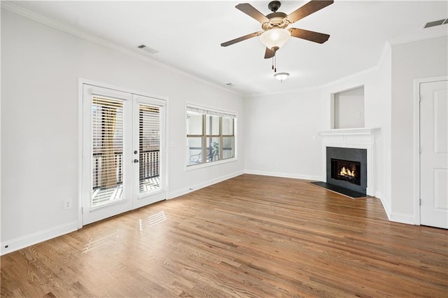 unfurnished living room with wood-type flooring, ornamental molding, a healthy amount of sunlight, and french doors