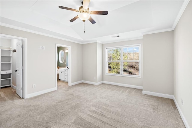 unfurnished bedroom featuring ceiling fan, ensuite bath, a raised ceiling, a spacious closet, and a closet