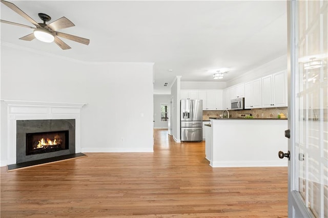 unfurnished living room with ceiling fan, light hardwood / wood-style flooring, and ornamental molding