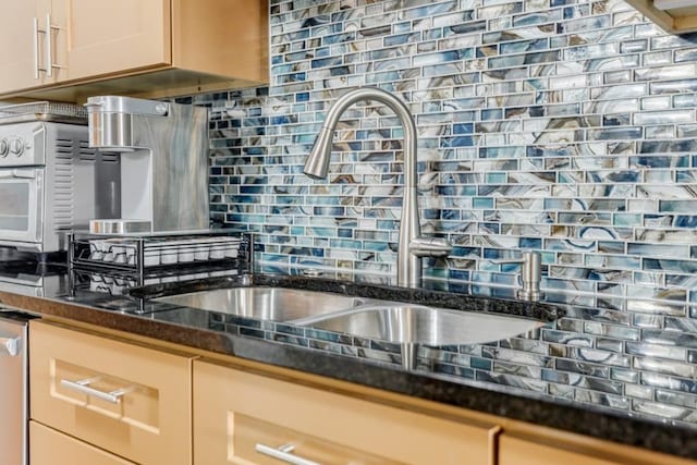 kitchen featuring tasteful backsplash, dark stone counters, and a sink