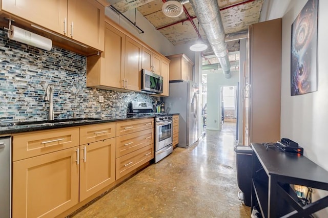 kitchen featuring decorative backsplash, appliances with stainless steel finishes, a sink, dark stone countertops, and concrete floors